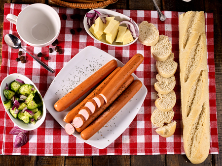 Sausage portion with bread baguette on table setting on checkered tablecloth and cup in farm style. Composition of meat products. Meat products that do not contain soy.の写真素材