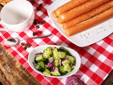 Sausage portion with bread baguette on table setting on checkered tablecloth and cup in farm style. Delightful, unique taste.の写真素材