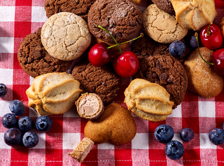 Cookies and sand biscuit on tier cake stand with blueberry chocolate on kitchen on picnic table in rustic natural style. Delightful, unique taste.の写真素材