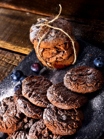 Serving food on slate onto wooden table. Oatmeal cookies biscuit with blueberry on picnic dark tiles countrylike. Chocolate chip cookies tied with string. Delightful, unique taste.の写真素材