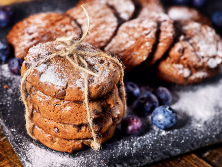 Serving food on slate onto wooden table. Oatmeal cookies biscuit with blueberry on picnic dark tiles countrylike. Chocolate chip cookies tied with string. How and from what make sweets.の写真素材