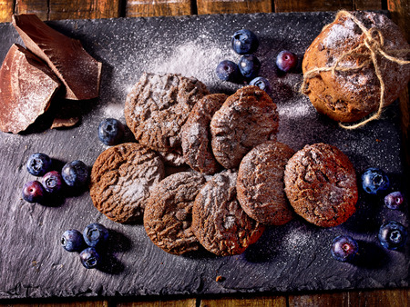 Serving food on slate onto wooden table. Oatmeal cookies biscuit with blueberry on picnic dark tiles countrylike. Chocolate chip cookies tied with string. Bakery products. Perfect product.の写真素材