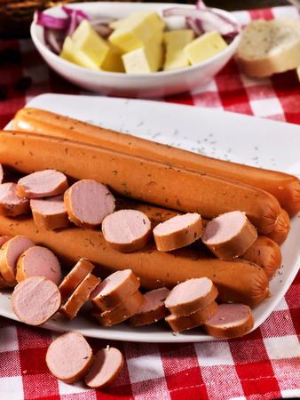 Sausage portion with bread baguette on table setting on checkered tablecloth and cup in farm style. High carbohydrate content.の写真素材
