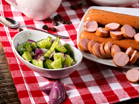 Sausage portion with bread baguette on table setting on checkered tablecloth and cup in farm style. Meat products help rapid growth of muscle mass.の写真素材