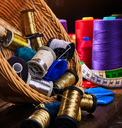 Sewing accessories coil threads and measuring tape in basket supplies close up. Process of creating beautiful clothes.の写真素材
