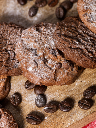 Oatmeal chocolate cookies with coffee grains, powdered sugar on kitchen cutting board with checkered fabric on wooden table in village style for picnic. Freshens usual recipe.の写真素材