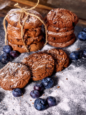 Serving food on slate onto wooden table. Oatmeal cookies biscuit with blueberry on picnic dark tiles countrylike. Chocolate Xmas holiday chip cookies. Perfect product. Beautiful table setting.の写真素材