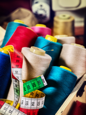 Coil threads for overlock and measuring tape in sewing supplies on serger background.