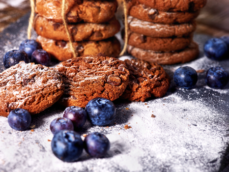Serving food on slate onto wooden table. Oatmeal cookies biscuit with blueberry on picnic. Chocolate Xmas holiday chip cookies. Perfect product. Best selection of confectionery products.の写真素材