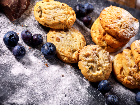 Serving food on slate onto wooden table. Oatmeal cookies biscuit with blueberry on picnic dark tiles countrylike. Chocolate Xmas holiday chip cookies tied with string. Composition of confectionery.の写真素材