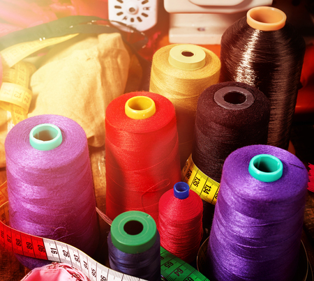 Coil threads for overlock and measuring tape in sewing supplies in on morning sunrise light sun flare.の写真素材