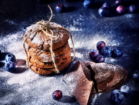 Serving food on slate onto wooden table. Oatmeal cookies biscuit with blueberry on picnic dark tiles countrylike. Chocolate Xmas holiday chip cookies tied with string. Cooking sweets at home.の写真素材