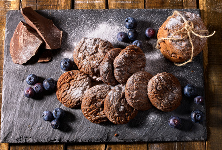 Serving food on slate onto wooden table. Oatmeal cookies biscuit with blueberry on picnic dark tiles countrylike. Chocolate chip cookies tied with string. Lunch in an inexpensive cafe.の写真素材