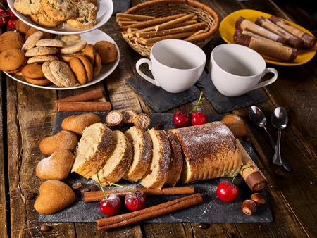Oatmeal and nut cookies heart shape and sand rolled biscuit on tier cake stand and cinnamon stick on kitchen on wood table in rustic style. Useful for digestion. Increase performance and moodの写真素材
