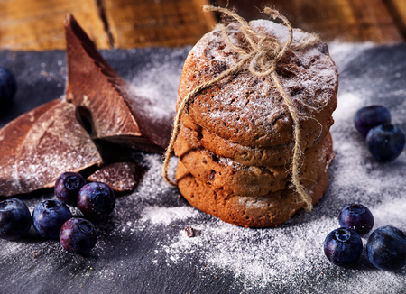 Serving food on slate onto wooden table. Oatmeal cookies biscuit with blueberry on picnic dark tiles countrylike. Chocolate Xmas holiday chip cookies tied with string. Homemade, delicious recipes.の写真素材