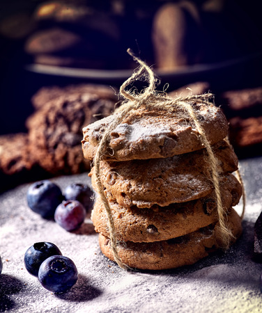 Bakers gonna bake. Serving food on slate. Oatmeal cookies biscuit with blueberry on dark tiles countrylike. Chocolate chip cookies tied with string shop on window display. Delightful, unique tasteの写真素材