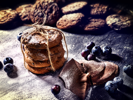 Bakers gonna bake. Serving food on slate. Oatmeal cookies biscuit with blueberry on dark tiles countrylike. Chocolate chip cookies tied with string shop on window display. Homemade, delicious recipes.の写真素材