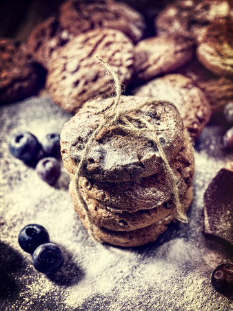 Bakers gonna bake. Serving food on slate. Oatmeal cookies biscuit with blueberry on dark tiles countrylike. Chocolate chip cookies tied with string shop on window display. Cooking sweets at home.の写真素材