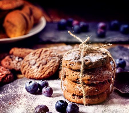 Bakers gonna bake. Serving food on slate. Oatmeal cookies biscuit with blueberry on dark tiles countrylike. Chocolate chip cookies tied with string shop on window display. High fat content.の写真素材