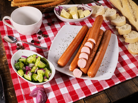 Sausage portion with bread baguette on table setting on checkered tablecloth and cup in farm style. Suitable product for breakfast, lunch and dinner.の写真素材
