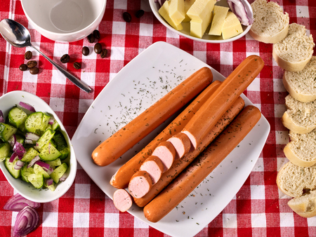Sausage portion with bread baguette on table setting on checkered tablecloth and cup in farm style. Meat products that don't contain soy.の写真素材