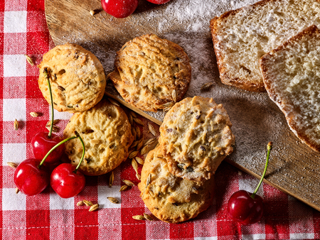 Oatmeal cookies and cherry on kitchen cutting board gingham checkered cotton fabric on table in village style for picnic. New dishes in expensive cafe. Culinary masterpiece at exhibition.の写真素材