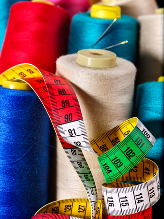 Coil threads for overlock and measuring tape in sewing supplies close up.の写真素材