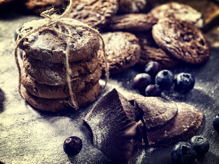 Bakers gonna bake. Serving food on slate. Oatmeal cookies biscuit with blueberry on dark tiles countrylike. Chocolate chip cookies tied with string shop on window display. Bakery products.の写真素材