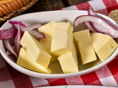 Cheese with onion on plate and checkered napkin in village style.の写真素材