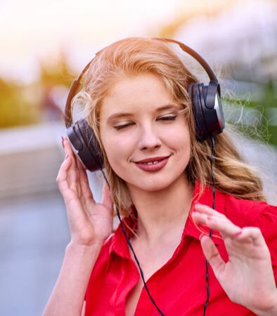 Student girl in headphone listen music after exam. Time to relaxin street city. Walking improves memory and concentration.の写真素材