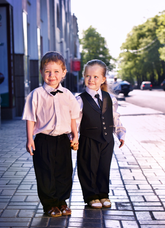 Children in business suits in center outdoor city street. Concept of boy and girl in smart suit hold hands.の写真素材
