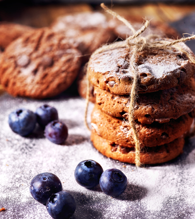 Bakers gonna bake. Serving food on slate. Oatmeal cookies biscuit with blueberry on dark tiles countrylike. Chocolate chip cookies tied with string shop on window display. High carbohydrate content.の写真素材