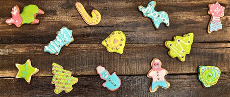Decorative Christmas cookies background on wooden board. Ginger biscuits Xmas tree and gingerbread man with icing on horizontal frame.の写真素材