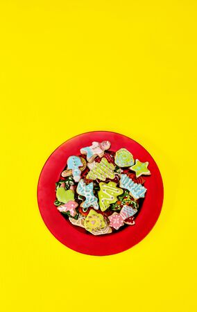 Christmas gingerbread cookies on red Xmas plate and yellow background. Long vertical design frame with copy space up.の写真素材