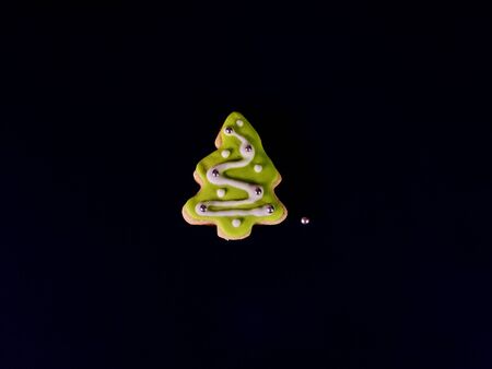 Decorative Christmas cookies. Ginger biscuits Xmas tree with icing on black background.の写真素材