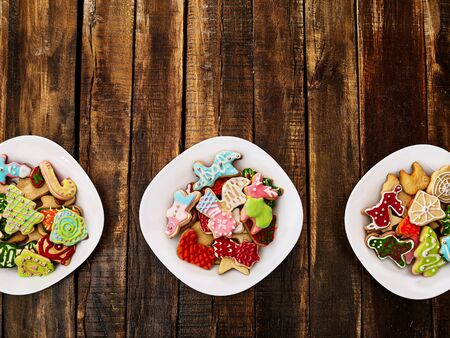 Christmas gingerbread cookies on three plates by wooden table close up. Top view long horizontal banner design frame with copy space top.の写真素材