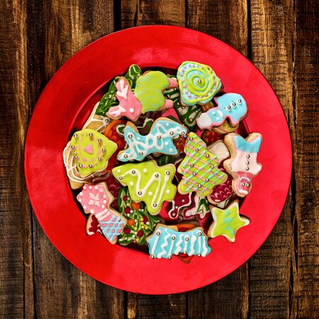 Christmas gingerbread cookies on red Xmas plate and wooden boards background . Top view close up of square design frame.の写真素材