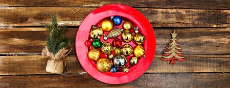 Christmas decorations design of Xmas balls ornaments on red plate with green tree on wooden boards. Horizontal long frame banner.の写真素材