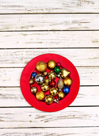 Christmas decorations design top view of Xmas balls ornaments on red plate onto vertical white wooden boards .の写真素材