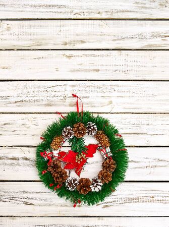 Christmas wreath with winter red flower in middle decoration hangs on white front door. Vertical frame with copy space top.の写真素材