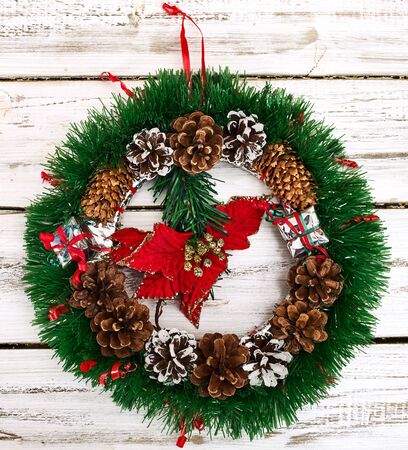 Christmas wreath with winter red flower in middle decoration hangs on white front door. Square frame.の写真素材