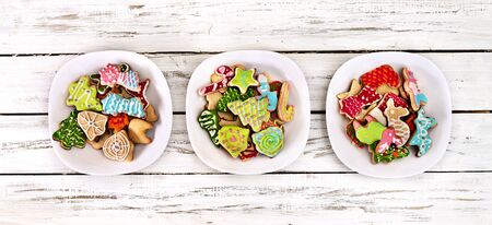Christmas gingerbread cookies on three plates group by white wooden table . Top view long horizontal banner design frame with copy space top.の写真素材