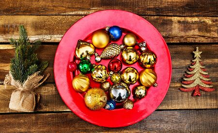 Christmas decorations design of Xmas balls ornaments on red plate with green tree on wooden boards. Horizontal frameの写真素材