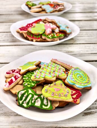 Christmas gingerbread cookies on three plates by white wooden table . Top view long vertical design frame.の写真素材