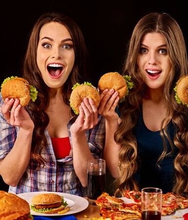 Group women eat best hamburger and pizza in burger bar . Friends take fast food drink cola and chatting.の写真素材