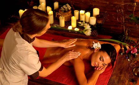 Shoulder and neck woman oil pressure massage by master acupressure therapy professiona with top view large group of candles in day spa.の写真素材