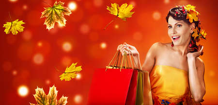 Autumn sale shopping bag banners maple leaves background with beautiful woman. Fashion dream in red fall color outside.の写真素材