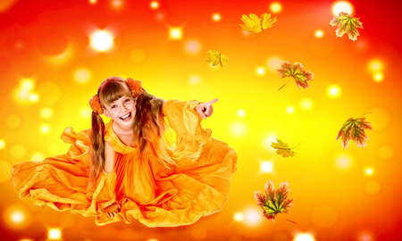 Autumn leaves background with child girl. Conceptual fashion dream in red fall color of september sun. Kid playing with leaves in fall.の写真素材