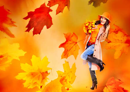 Autumn sale banners leaves background with beautiful woman wear in coat and hat, high heel boots. Girl holding maple bouquet in hand.の写真素材