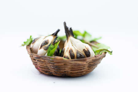 Roasted Garlic Cloves and Bulb with green leafs in white background.の写真素材